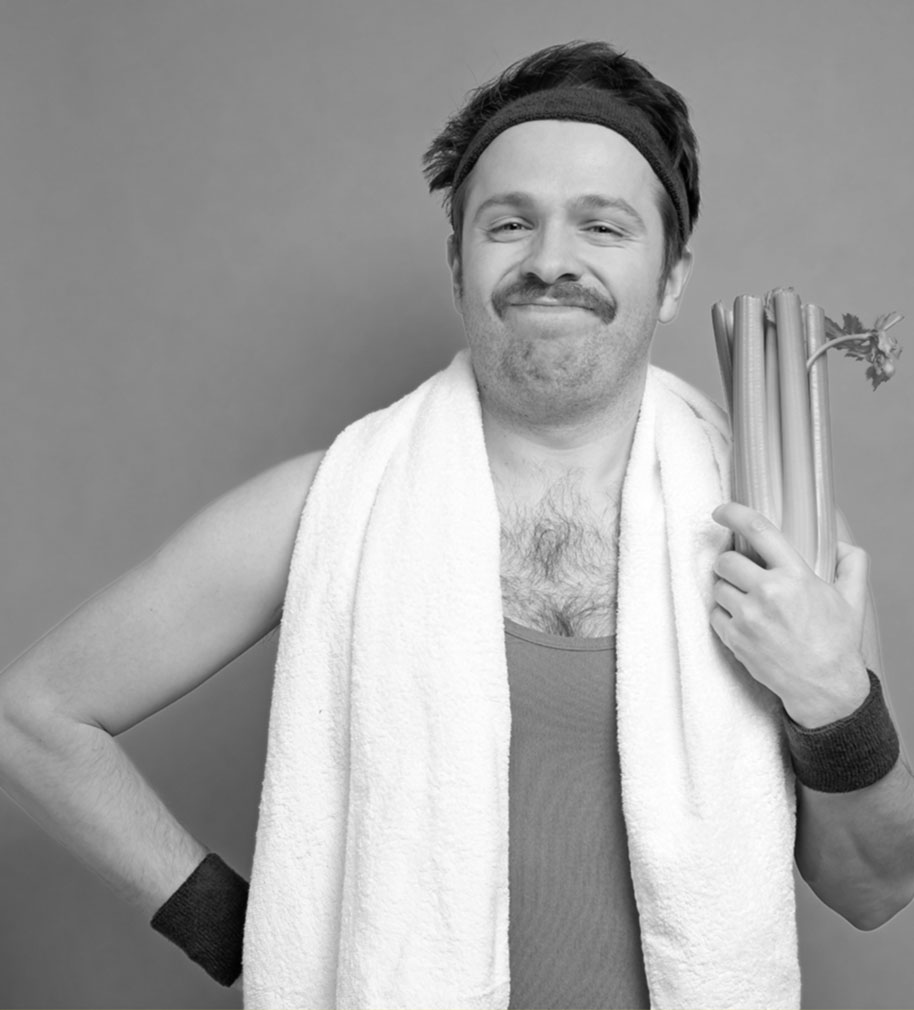 A mustached man wearing sports attire and holding celery