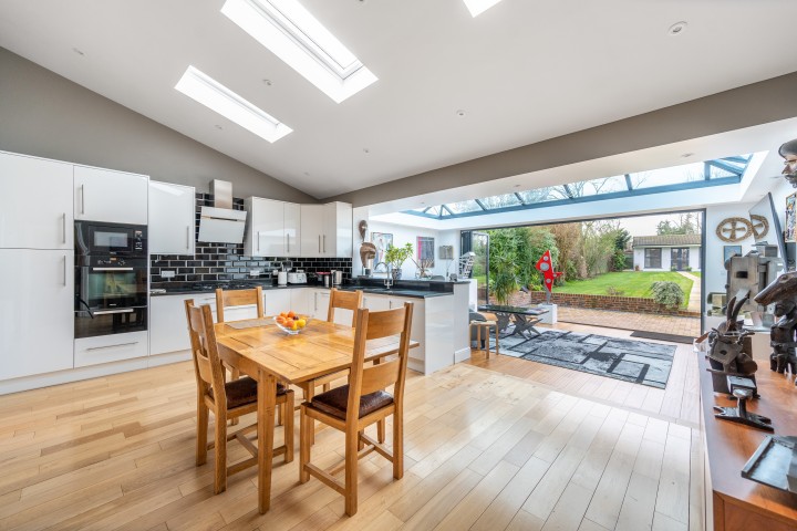 Spacious kitchen leading to a conservatory, opening out to a garden and summer house beyond.